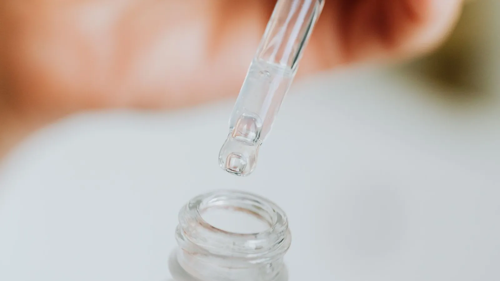 Pipette mit klarer Pflegeflüssigkeit über einem Glasfläschchen