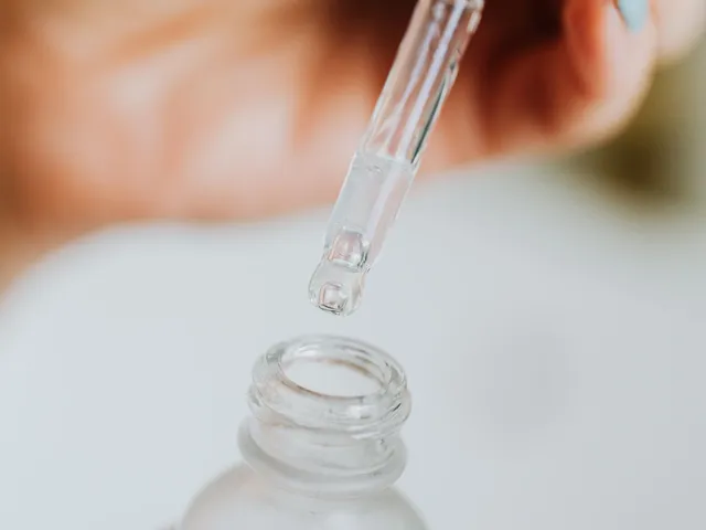 Pipette mit klarer Pflegeflüssigkeit über einem Glasfläschchen