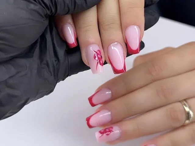 Hand mit elegant gestalteten roten und weißen Fingernägeln